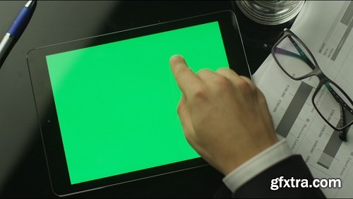 Businessman using tablet pc with green screen which lying on the table top view