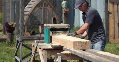 Carpenter planing wooden beam