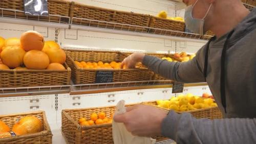 Videohive - Man with Medical Face Mask Selects Mandarins in Store. Guy Choose Fruits in Supermarket. Purchase - 26163408