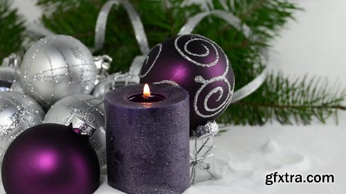 Christmas background with candle and decorations.Purple and silver Christmas balls over fir tree branches in the snow
