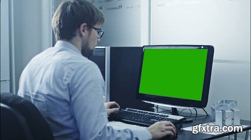 Engineer is working on computer display with green screen great for mock up usage