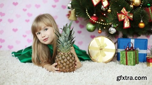 Child looks out over the pineapple lying on the floor near the christmas