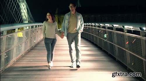 Couple walking holding hands on bridge in the night