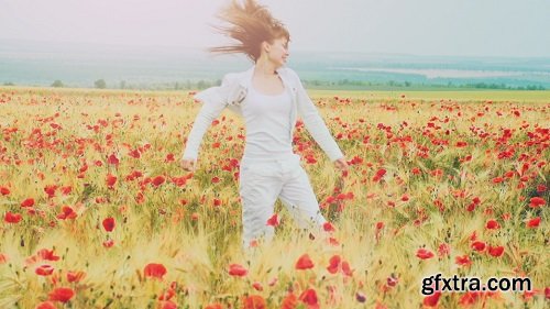 Young attractive woman dressed in white clothes is running-through a poppies field feeling happy and free slow motio filmed at 250-fps