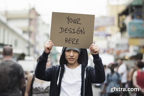 Young asian man holding mockup placard outdoors