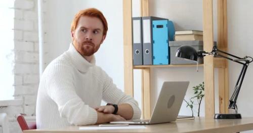 Man with Red Hairs Waiting at Work for Late Customer
