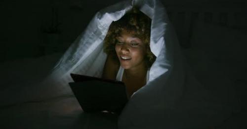 Woman Using Tablet Under Blanket