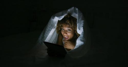 Excited Woman Under Blanket with Tablet
