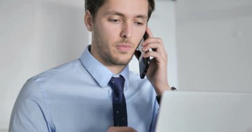 Close Up of Young Businessman Talking on Phone at Work