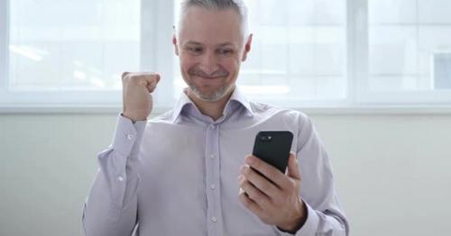 Middle Aged Man Excited for Success while Using Smartphone