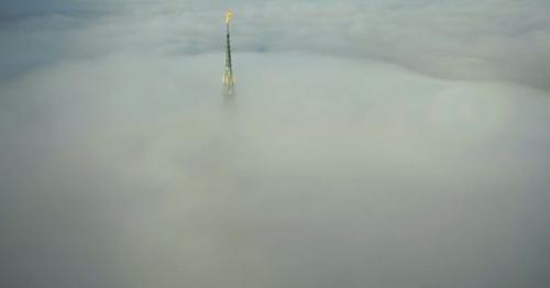 Drone Is Flying Away From Amazing Mont Saint Michel Castle Steeple Statue Above Clouds in the Sky