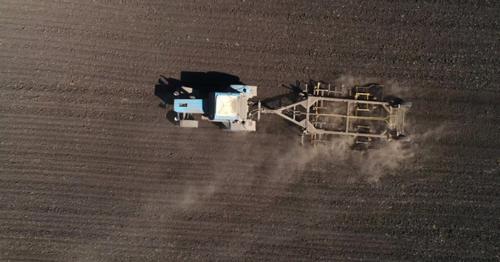 Aerial View of Agricultural Tractor Cultivating Field. Tractor At Work.