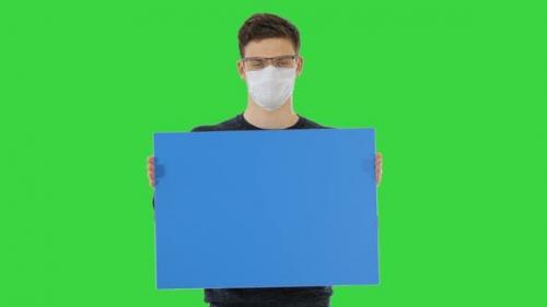 Videohive - Young Man in Medical Mask Showing and Displaying Placard on a Green Screen, Chroma Key - 26313180