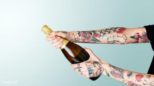 Tattooed hand holding a bottle of champagne - 2053142