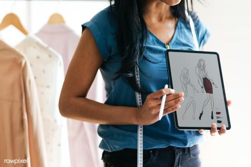 Fashion designer holding a tablet with a design drawing - 1220738