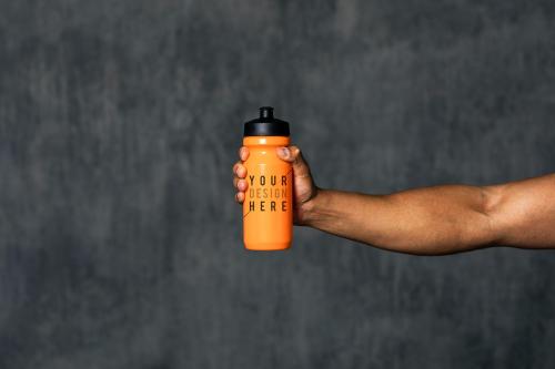 Muscular man holding an orange water bottle mockup - 1222538