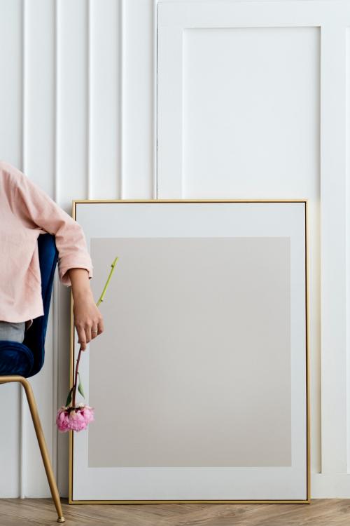 Woman holding a flower sitting by a frame mockup - 1210101