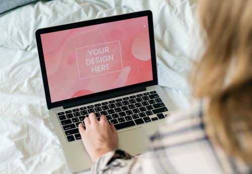 Woman using a laptop screen mockup in bed - 894810