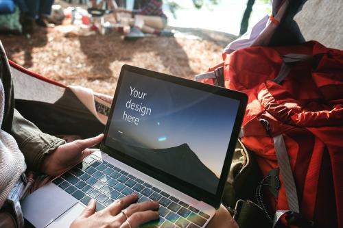 Woman using a laptop screen mockup at a camping trip - 894863