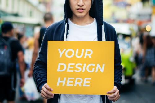 Young Asian man holding a placard mockup outdoors - 894887