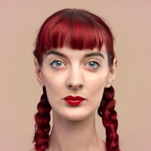 Portrait of beautiful woman with braided red hair on a blank beige wall - 2209634