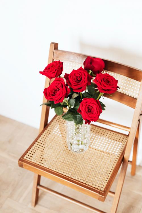 Red roses in a glass vase on a wooden chair - 2282000