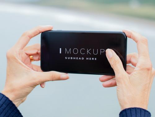 Woman holding a mobile phone mockup outdoors - 528226