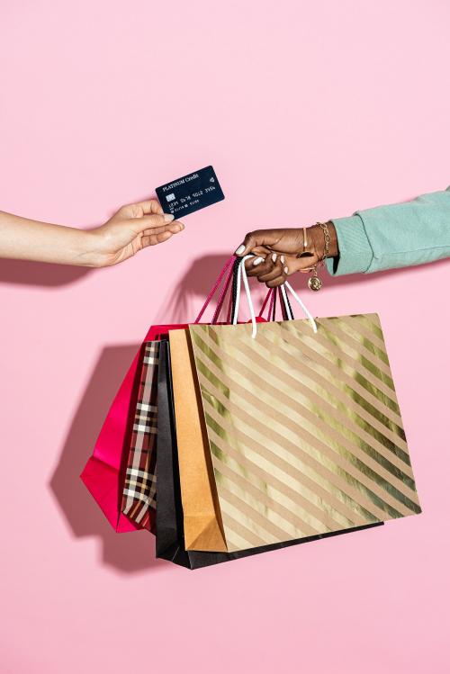Woman with shopping bags and a credit card against a pink background - 2054334