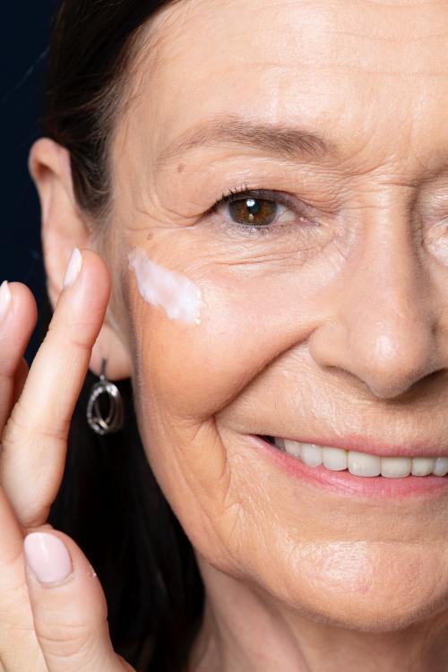 Elderly woman applying facial cream - 2230105