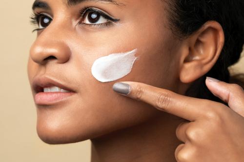 Closeup of a beautiful woman using a moisturizing cream for skincare routine - 2054076