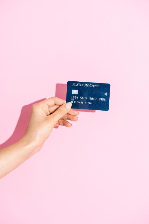 Woman holding a credit card against a pink background - 2054333