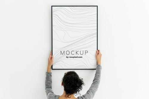 Woman putting up an art piece mockup at home - 503014