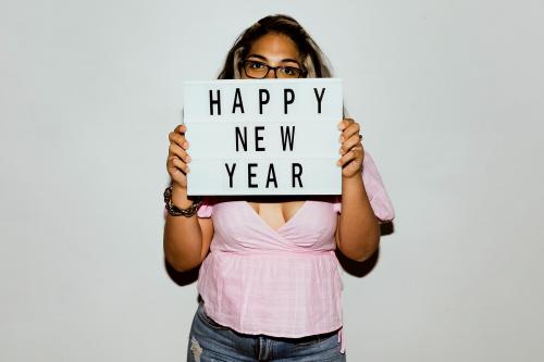 Woman with eyeglasses raising a happy new year board - 2097473