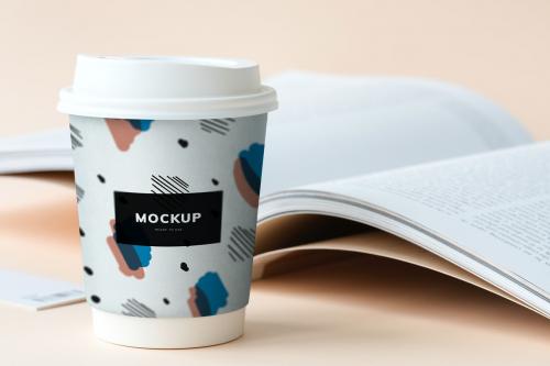 Takeaway coffee cup mockup on a table with an open book - 502753
