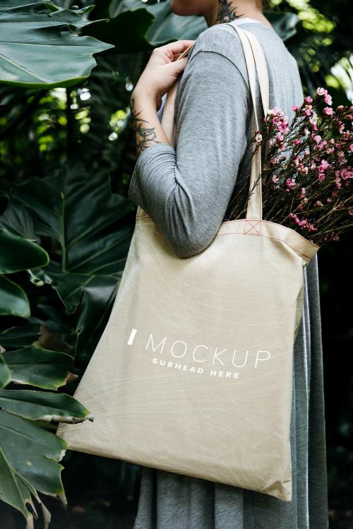 Woman carrying a tote bag mockup with flowers - 502797