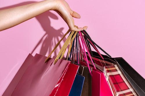 Woman carrying shopping bags against a pink background - 2054433