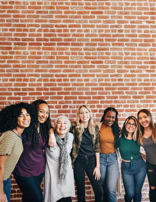 Diverse women standing together by a brick wall - 2027898
