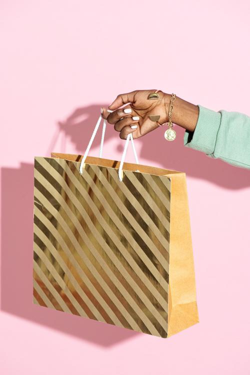 Woman carrying a shopping bag against a pink background - 2054392