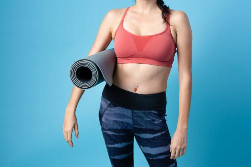 Portrait of sportive woman holding a yoga mat - 2255285