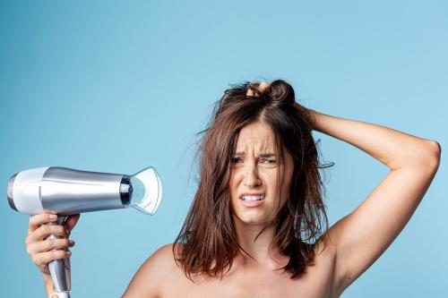 Frustrated woman using a blow dryer - 2230333