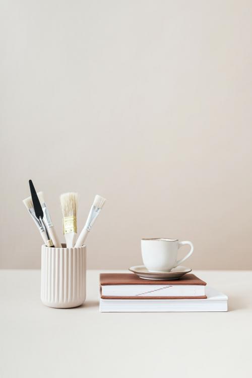 Paintbrushes and cup on top of books - 2254327