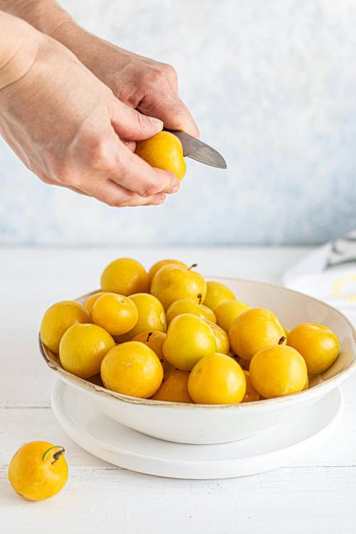 Woman slicing mirabelle plums in the kitchen - 1225259
