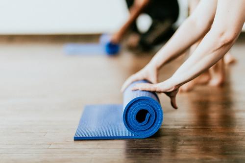 Yogi rolling her blue yoga mat - 1225132