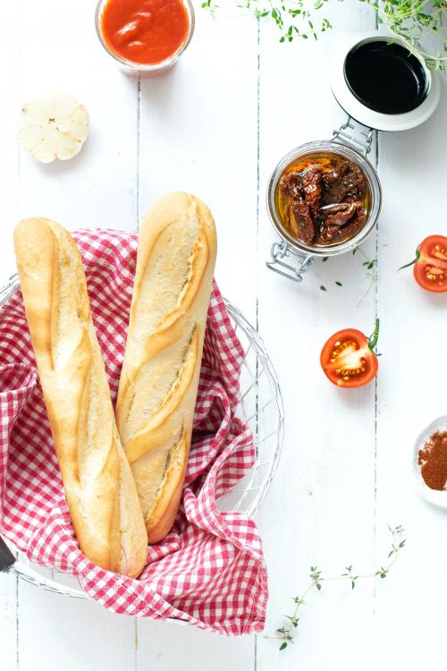 Fresh baguette in a basket by sun-dried tomatoes - 1225297