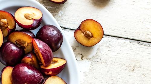 Sliced organic plums in a bowl - 893649