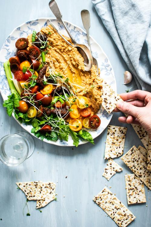 Woman dipping crackers in a hummus salad - 893633