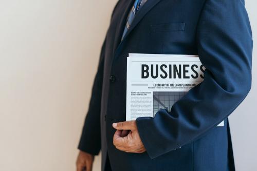 Businessman standing with a newspaper - 1225423