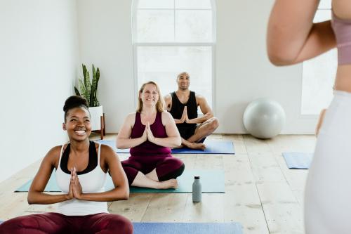 Cheerful people doing a Sukhasana pose in a studio - 1226934