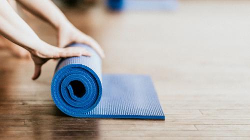 Yogi rolling her blue yoga mat - 1225136