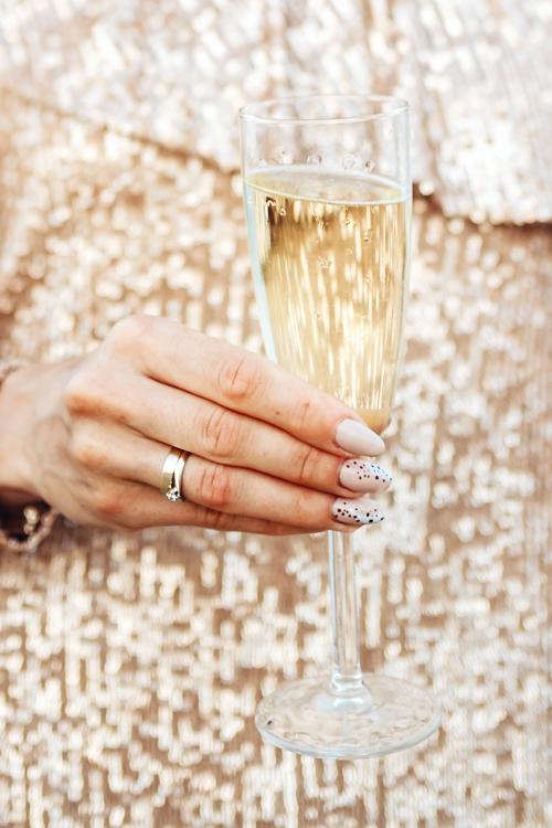 Closeup of a woman in a gold dress having a glass of champagne - 1228582